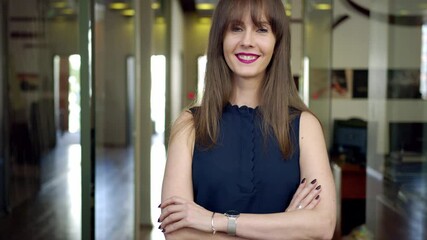 Businesswoman in office - happy confident young woman standing on office corridor, smiling. Career and employment.