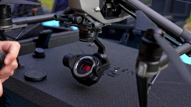 Drone pilot equip DJI Inspire professional drone with Zenmouse camera and lens before flying. Editorial video.