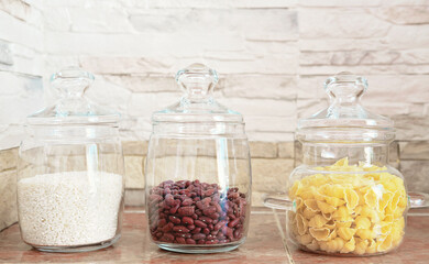 food storage and order in a kitchen. glass containers for grocery on a shelf. front view