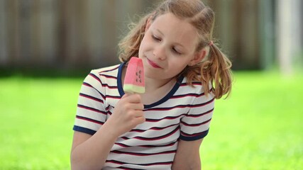Happy little teen girl lick refreshing ice cream  and joying sunny summer time at green backyard