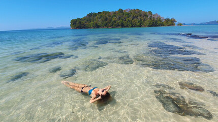 Fototapeta na wymiar Young woman lying on the beach. Fashion model posing on a tropical island in sunglasses.
