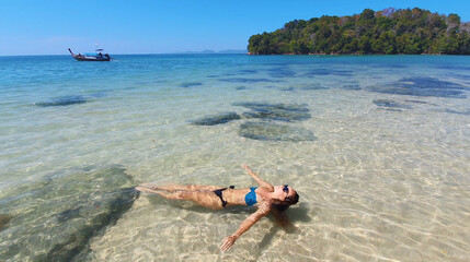 Fototapeta na wymiar Young woman lying on the beach. Fashion model posing on a tropical island in sunglasses.