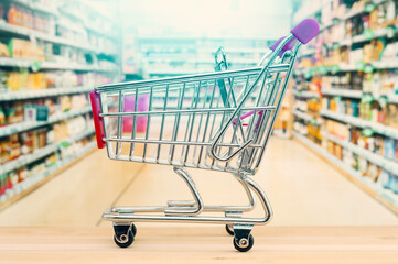 Empty shopping trolley cart on blurring supermarket aisle background