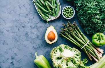 Healthy organic green food, assortment of fresh vegetables: Avocado, lettuce, broccoli, green peas, pepper, celery, kale, asparagus and other. Top view with copy space.