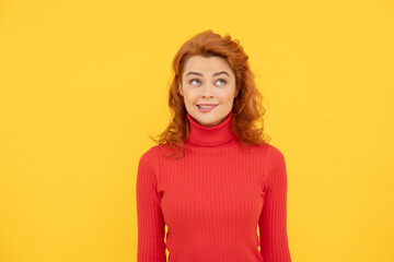 pretty dreamy redhead woman face portrait bite her lip on yellow background, emotions