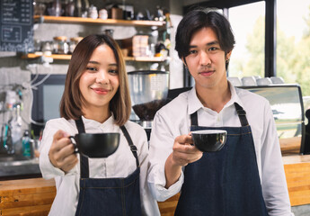 Two asian coffee waitress making cup of hot coffee latte in coffee shop cafe. Barista working with coffee machine in shop.