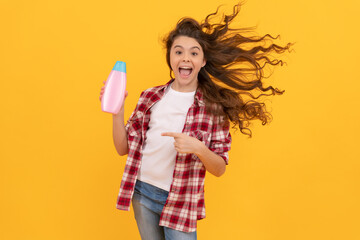 happy teen girl with long curly hair hold shampoo bottle, fun
