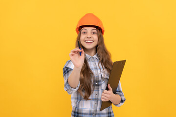 happy teen girl in helmet and checkered shirt making notes on clipboard, childhood