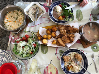 Brazilian lunch at home with rice and vegetables, fish and chips, beans, salad and farofa.