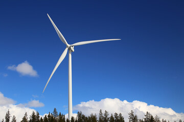Wind turbine over forest and clouds with blue sky - obrazy, fototapety, plakaty