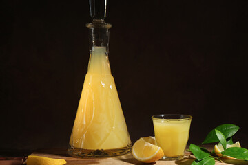 Alcoholic drink limoncello on dark background. Decanter and shot glass of limoncello Italian lemon...