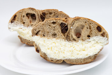 New York City Cinnamon Raisin Bagel Halves filled with Cream Cheese on a White Plate