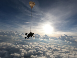 Tandem jump with an amazing sun at the background and clouds