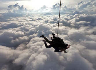 Tandem jump with an amazing sun at the background and clouds