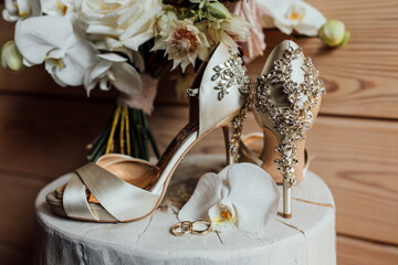 The bride's shoes. There are gold rings and flowers on the table. Wedding accessories.