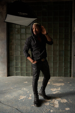 Stylish african handsome man in black clothes standing and posing in urbam interior of concrete and glass