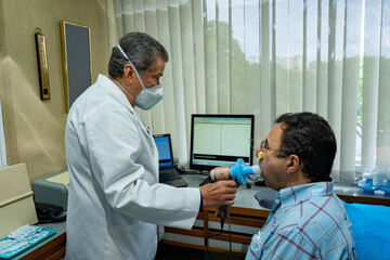 Mature man performing pulmonary function test and spirometry in doctor office