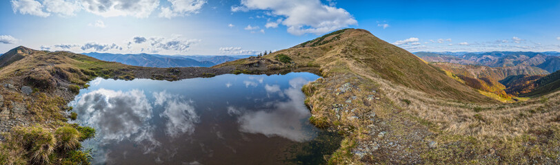 Small picturesque lake with clouds reflections at the  Strymba Mount. Beautiful autumn day in Carpathian Mountains near Kolochava village, Transcarpathia, Ukraine.