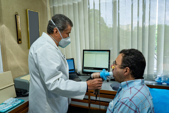 Mature man performing pulmonary function test and spirometry in doctor office