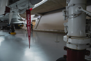 Red ribbon stating Remove Before Flight, attached to a fighter jet as a security mechanism that should be removed before usage