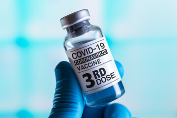COVID-19 Vaccine Vial for vaccination tagged with 3rd dose. Doctor with Coronavirus vaccine bottle...
