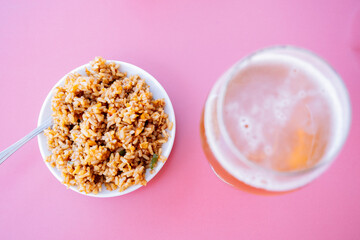 Fototapeta na wymiar Rice dish top with a beer on a pink table.