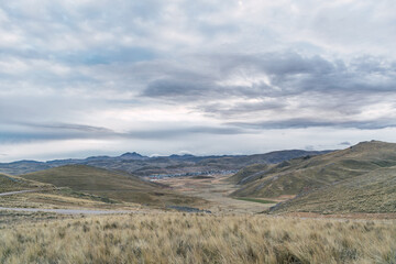 atardecer en un poblado de los andes de peru acompañado de la paja amarilla de los andes y al fondo viendose un poblado del medio rural