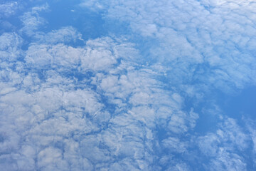 Fluffy sky clouds lit by afternoon sun, as seen from commercial airplane flying over