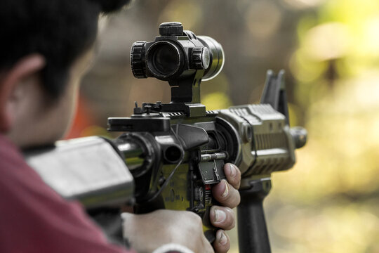 Shooter aiming assault rifle at target.