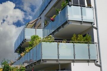 Balkon mit Edelstahl-Geländer und Sichtschutz aus Milchglasplatten an der Fassade eines modernen...