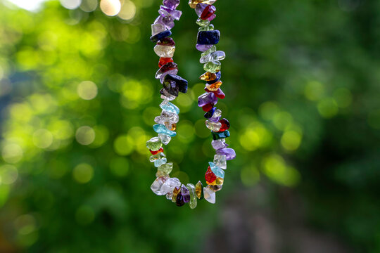 Crystal gemstone bracelet talisman charged in the sunlight, nature green bokeh, chakra talisman