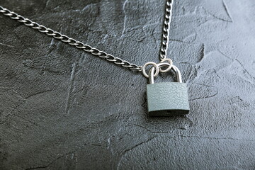 Fototapeta na wymiar locked padlock with chain on black concrete background with copy space
