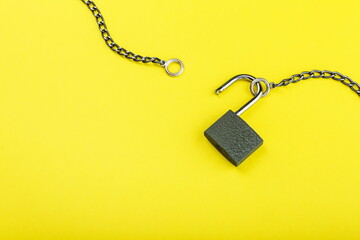 unlocked padlock with chain on yellow background with copy space