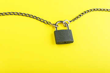 Fototapeta na wymiar locked padlock with chain on yellow background with copy space