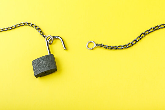 unlocked padlock with chain on yellow background with copy space