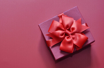 Holiday concept banner with hand made gift box, bow on a purple background with space for text.