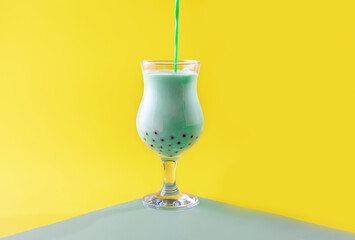 a glass of matcha tea with tapioca balls on a yellow background