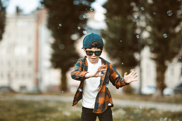 Fototapeta na wymiar boy in town wearing sunglasses. Baby plays with soap bubbles