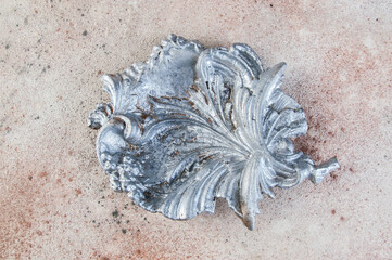 Old aluminum leaf ashtray on concrete background.
