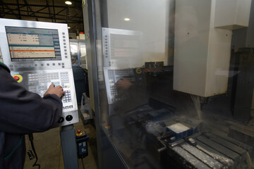 close up a worker hand or engineer introducing a program into a modern CNC machine. The concept of...