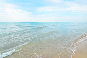 Empty beach in Italy. No people, blue waters, blue sky and white sand. Tropical beach with green ocean and small wave in daylight. Wave of the sea on the white sand beach.