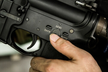 Finger selecting Rifle gun selective switch on safe mode position