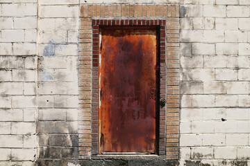 rusty red old metal steel door in a back alley concrete block abandoned warehouse building