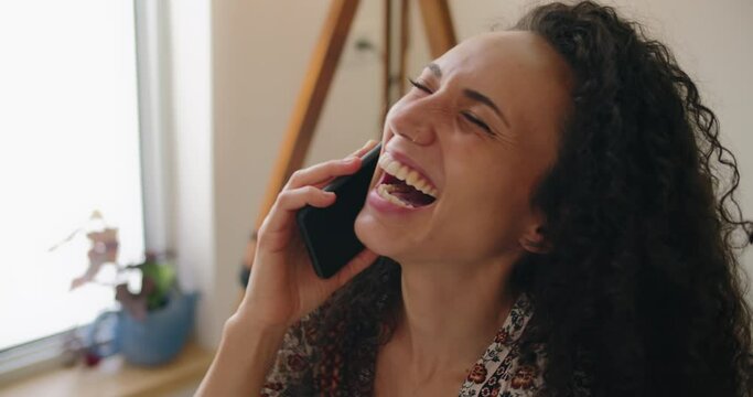 Beautiful mixed race girl laughing while having a conversation on the phone. Slow motion, handheld, close up. 
