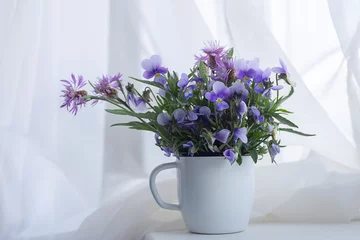Foto op Canvas Delicate bouquet of flowers pansies in a cup on the windowsill © Natalia S.