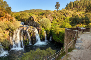 Obraz premium Poço da Broca waterfall in Serra da Estrela Natural Park, Barriosa, municipality of Seia in Portugal, with a viewpoint in the foreground, at the end of a spring day.