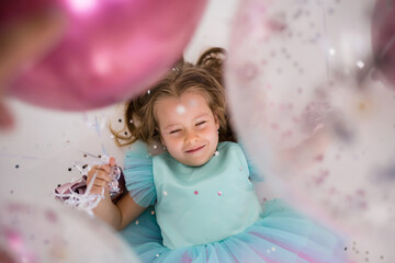 a little blonde girl lies with her eyes closed on a festive background. Festive attributes