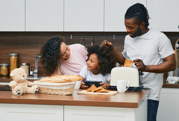 African American family with girl child are prepared sandwiches in the kitchen together, toasting bread and spending fun time together