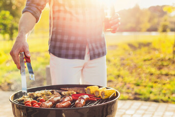 Delicious assorted grilled meat and sausages, with grilled vegetables with smoke and flame outdoors in the park in