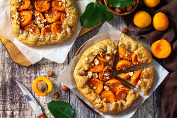 Healthy pastries gluten free, made from rye flour, diet food. Apricot galette with hazelnuts, summer fruit pie with nuts on a rustic table. Top view flat lay background.